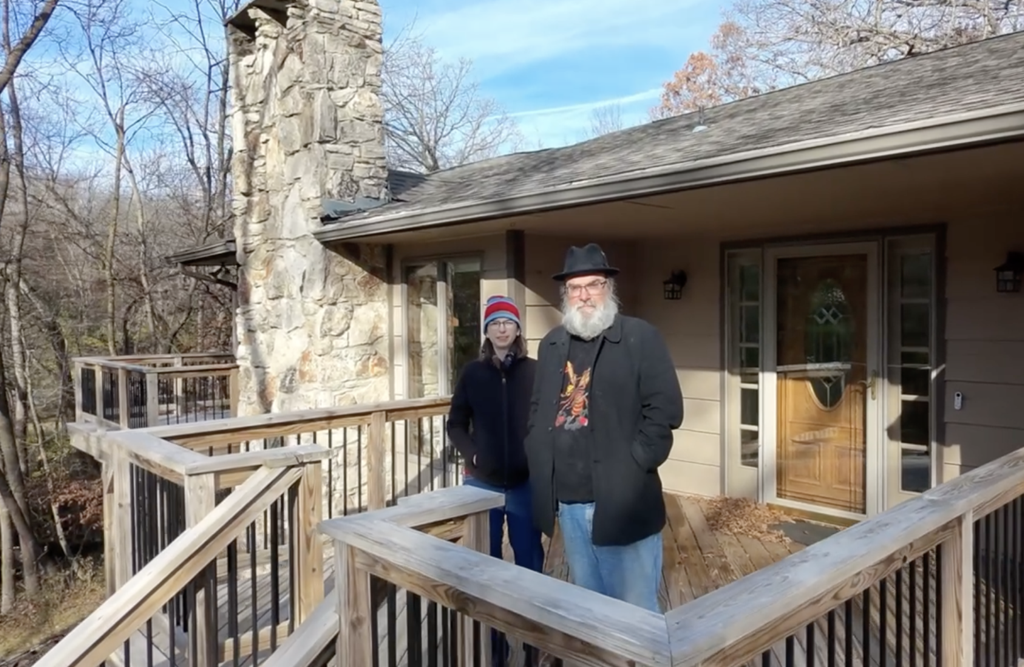 Erin and Christopher standing on the front porch of their house in Iowa.